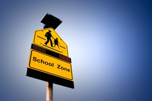 A road sign shown it's a school zone on gradient background.