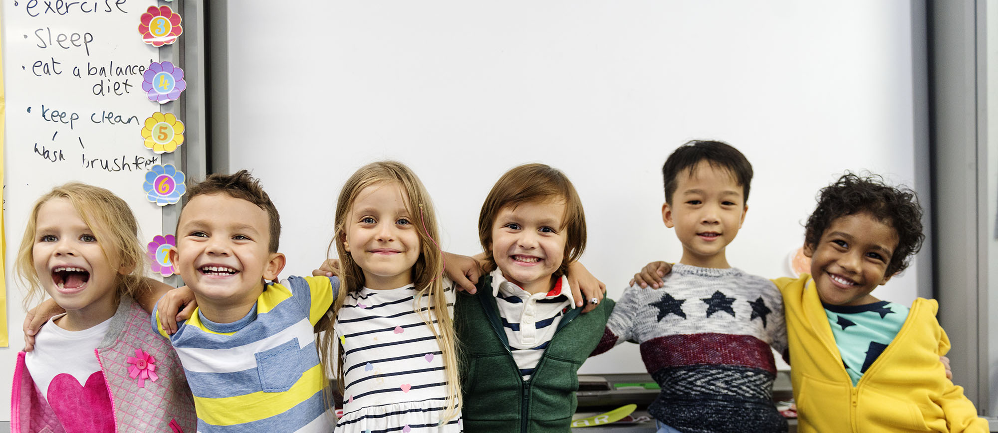 Group of diverse kindergarten students standing together in clas
