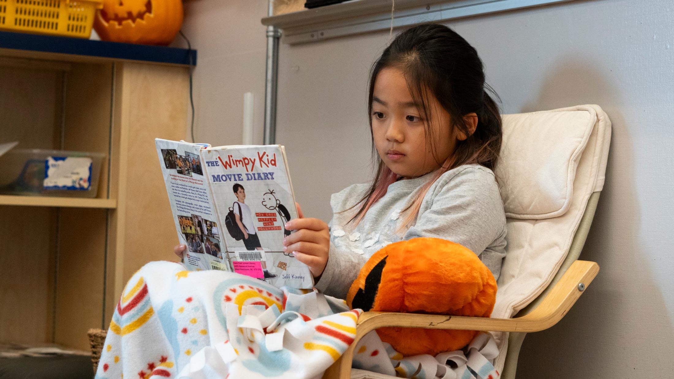 A girl reading a book called: The Wimpy Kid